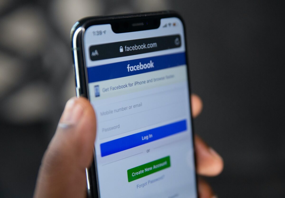 Una mano impugna uno smartphone con aperta l'app di Facebook